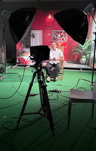 A camera on a tripod facing a guest on set